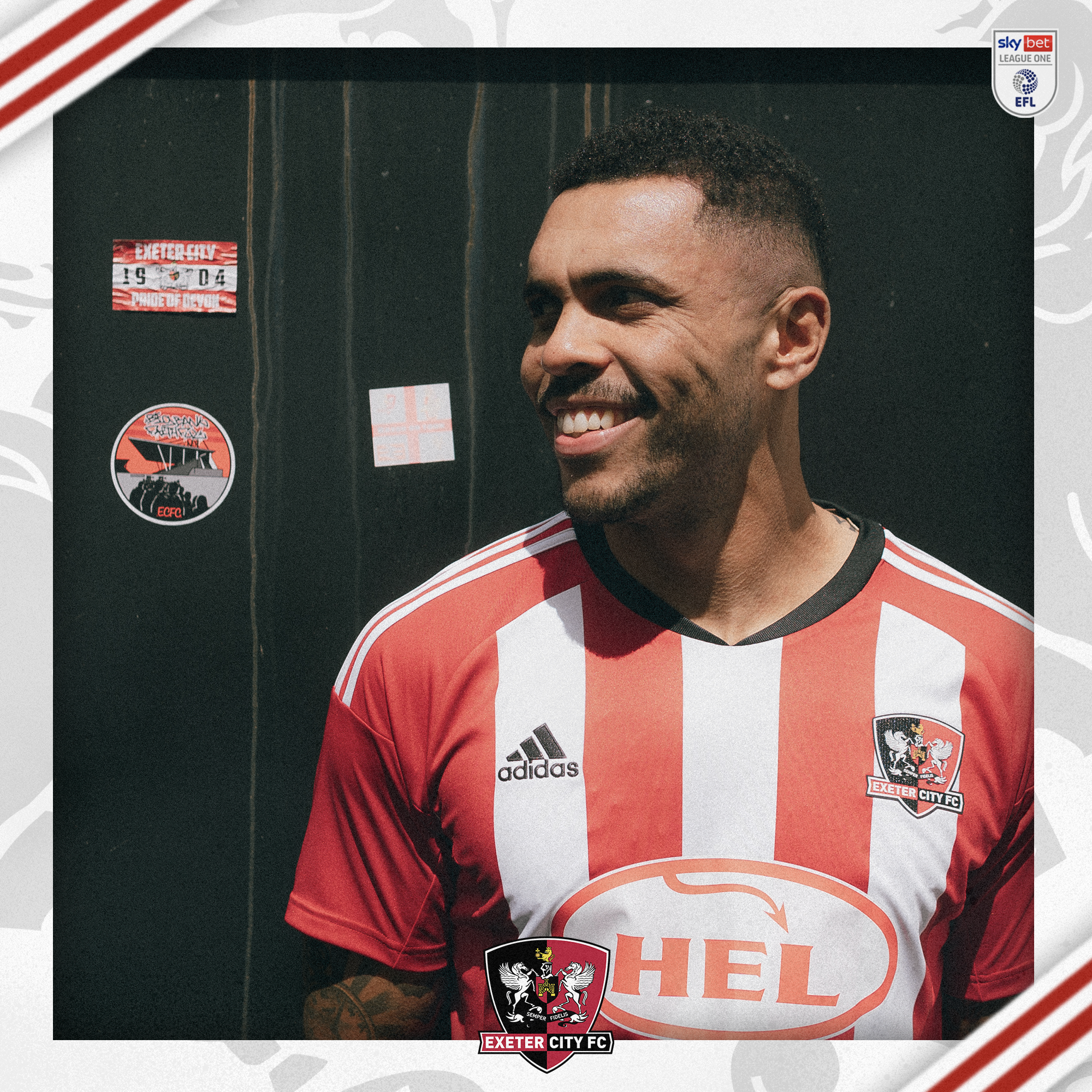 Josh Magennis in Exeter kit leaning against a black gate, looking to his right