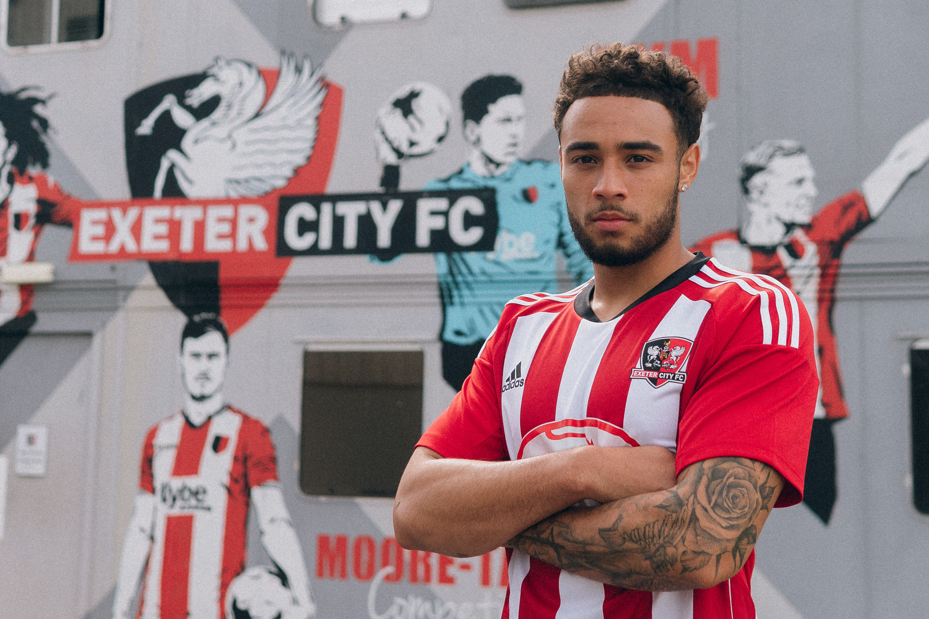 Image of Jay Bird stood in front of the ECFC academy mural