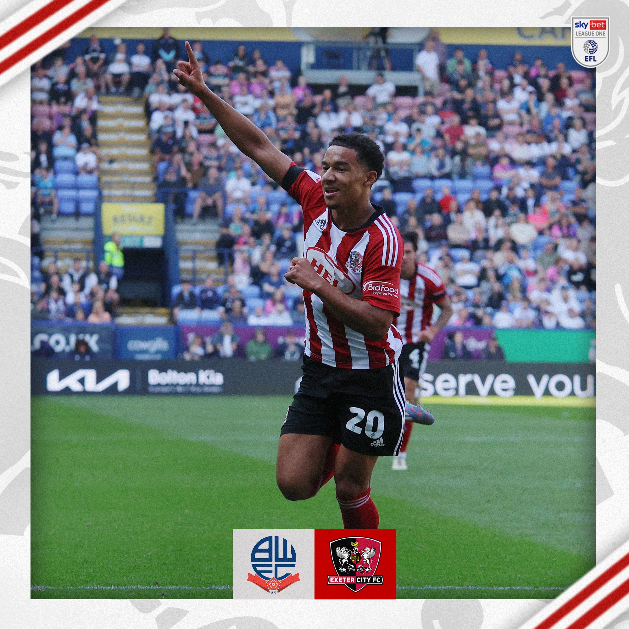 Kamari Doyle celebrating his first Exeter City goal. He's wearing a red and white kit and has one arm in the air, pointing.