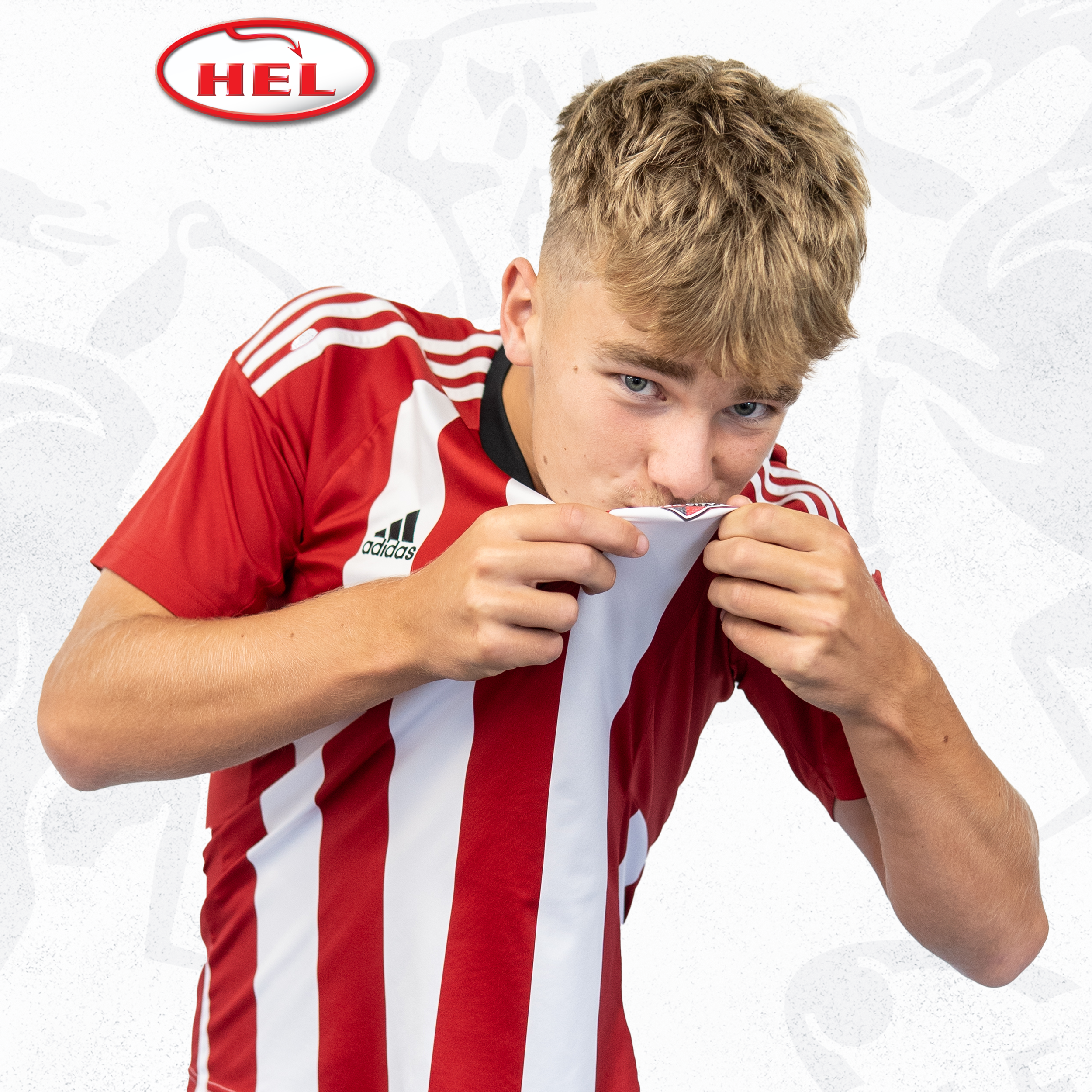 Under-18s player profile picture of Harry Crees. He's wearing the red and white home shirt, and is lifting up the badge to kiss it. He has a blonde fringe which is short at the sides.