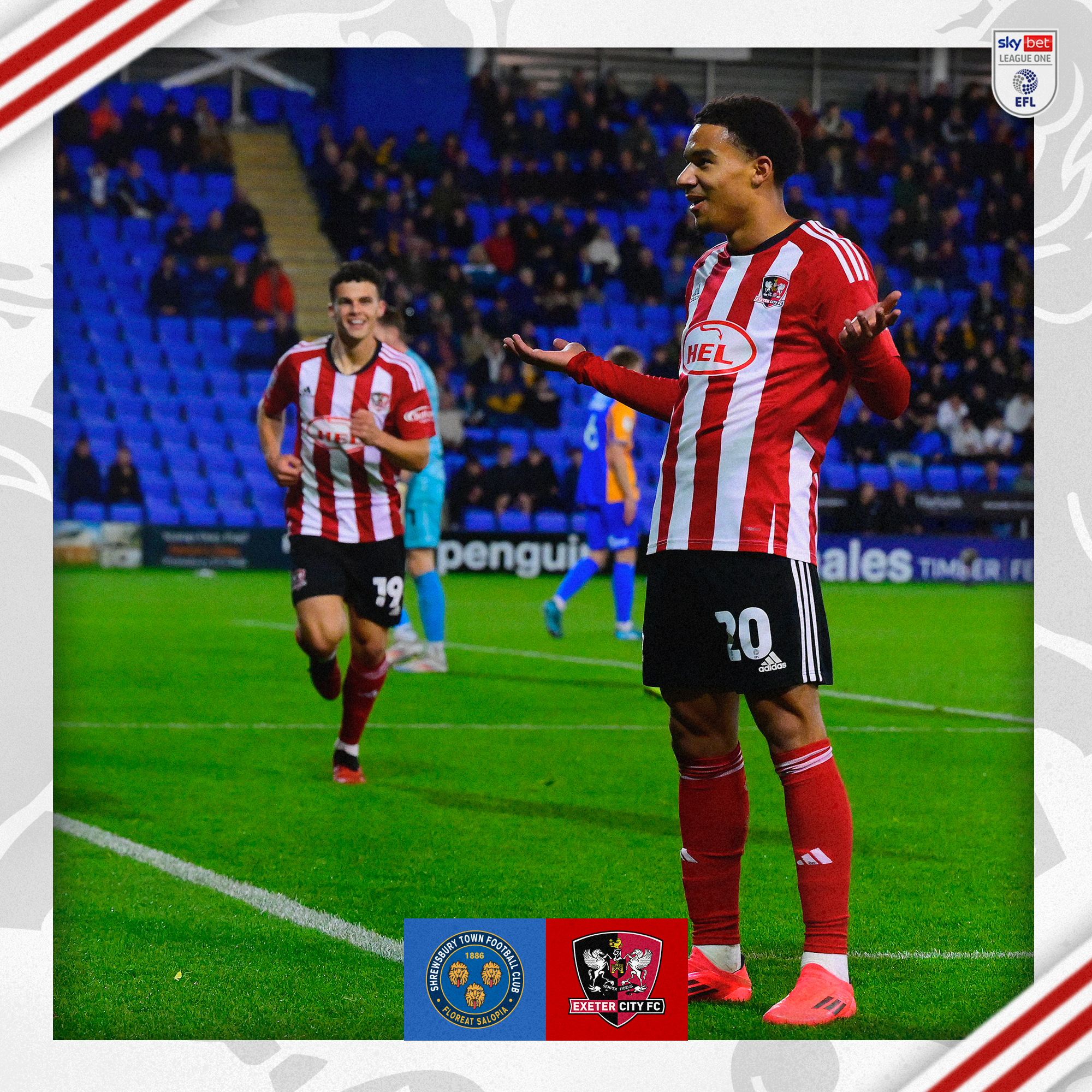 Kamari Doyle, in his red and white home kit, celebrating scoring the opener by shrugging in front of the Shrewsbury home end. You can see Sonny Cox out of focus running towards him to celebrate.