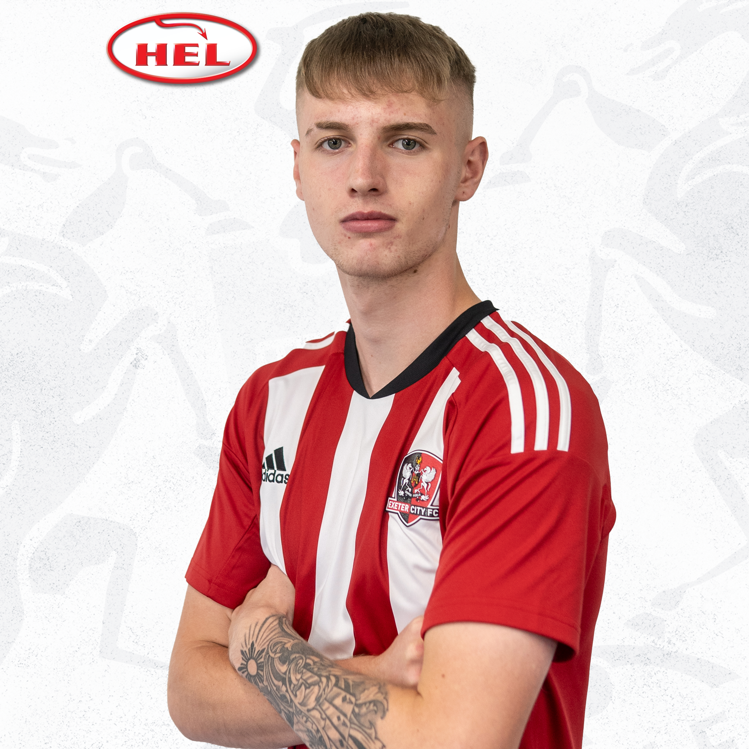 Profile Picture for Kieran Wilson. He's in his red and white home kit, standing with his arms folded looking at the camera. He's got one arm tattooed in a sleeve and short blonde hair in a fringe. The HEL logo is in the corner.