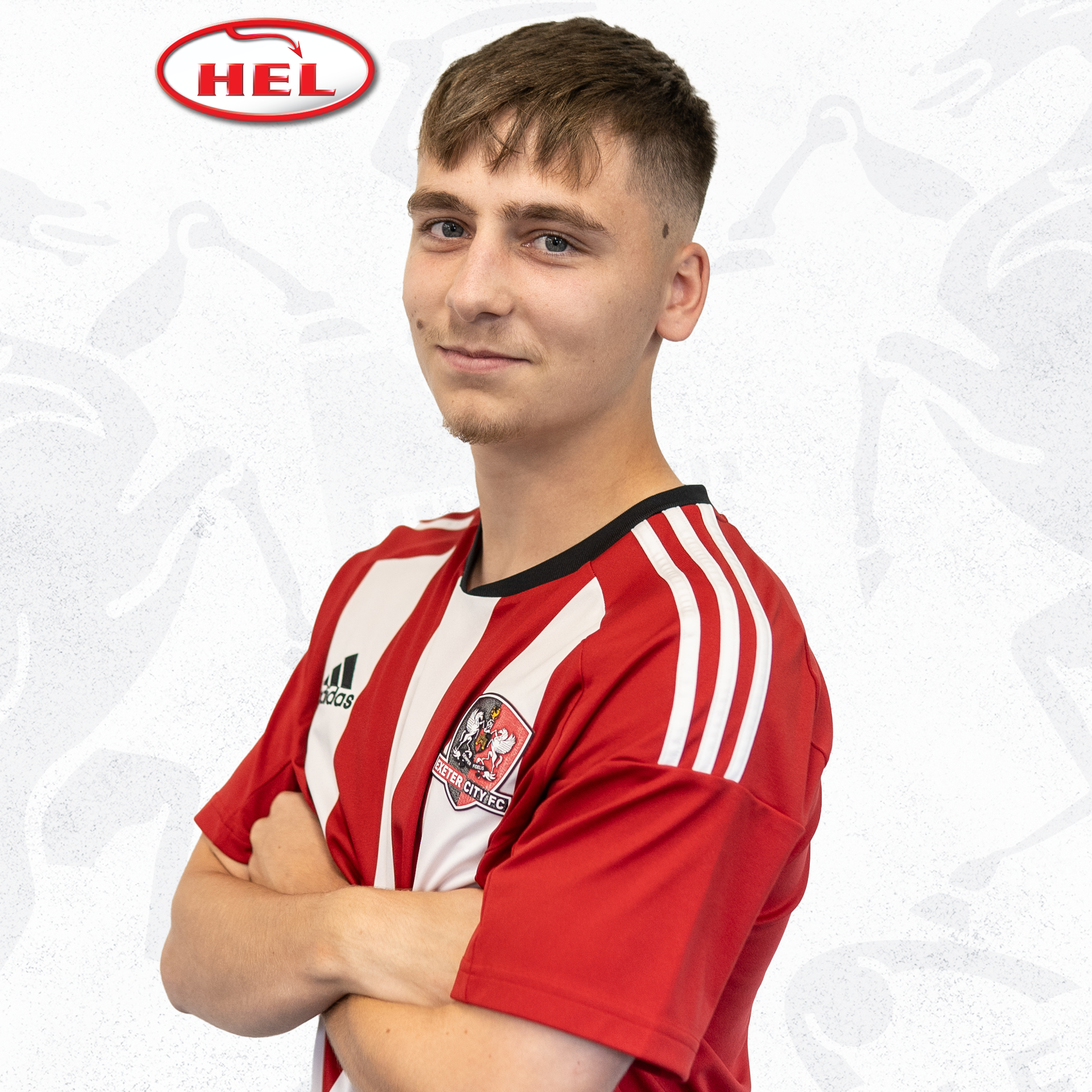 Liam Oakes profile picture. He's standing side on looking at the camera with his arms crossed over his red and white home kit. The HEL logo is in the corner. 