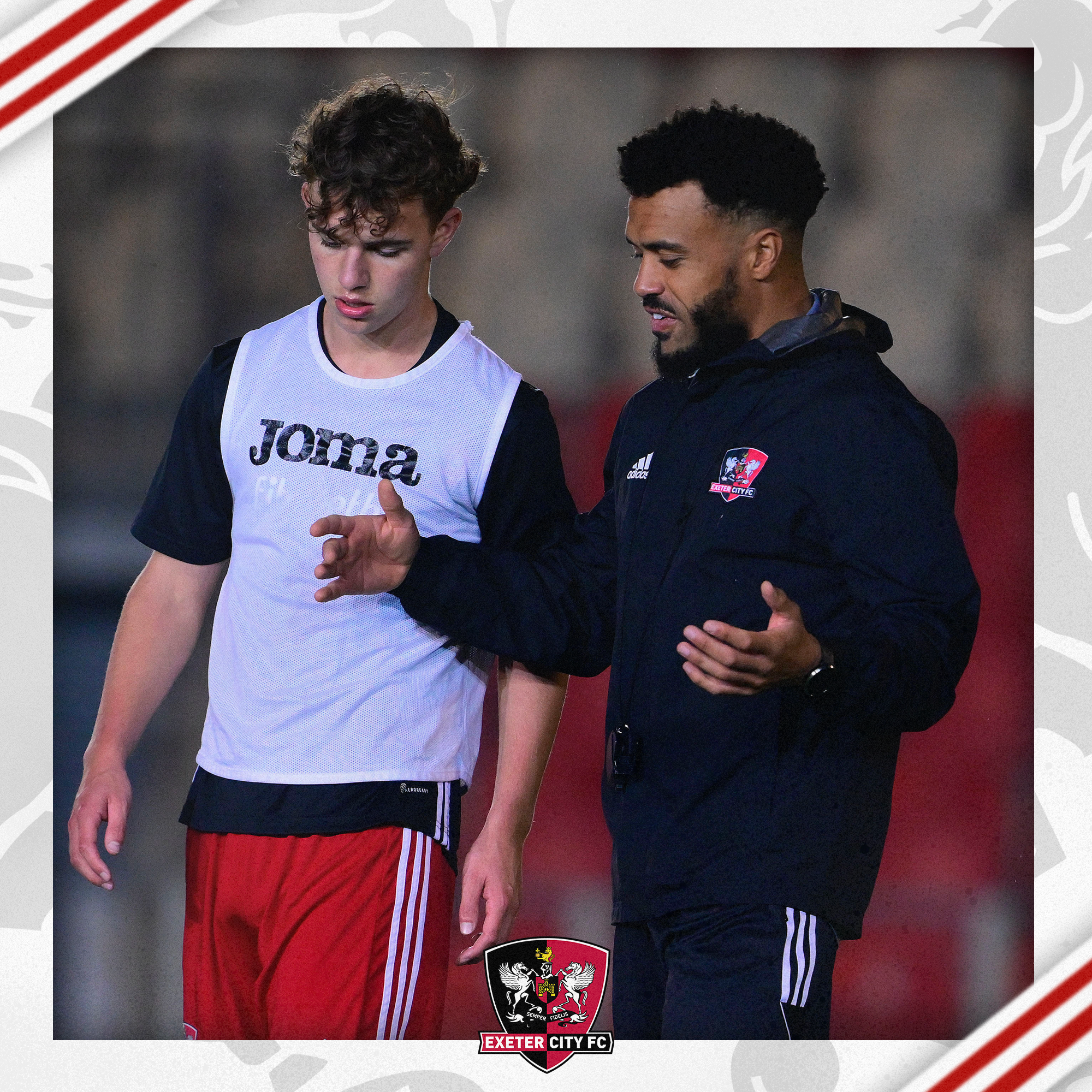 Image of Nicky Ajose, wearing a black coaches tracksuit, talking to a player, Jacca Cavendish, who's wearing a white bib over a black shirt in a warm up.