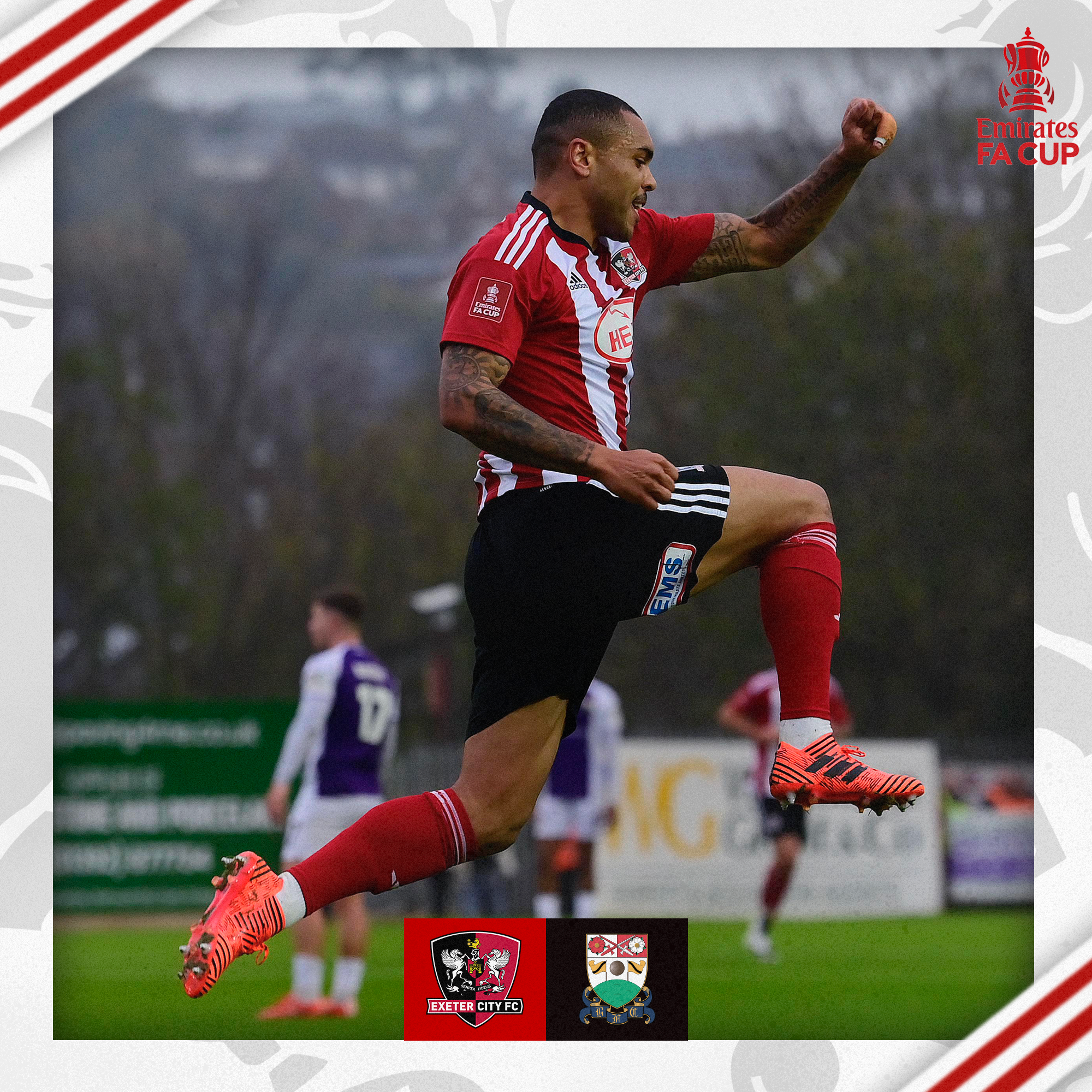 Josh Magennis, in his red and white home shirt, jumping in celebrating with a fist in the air.