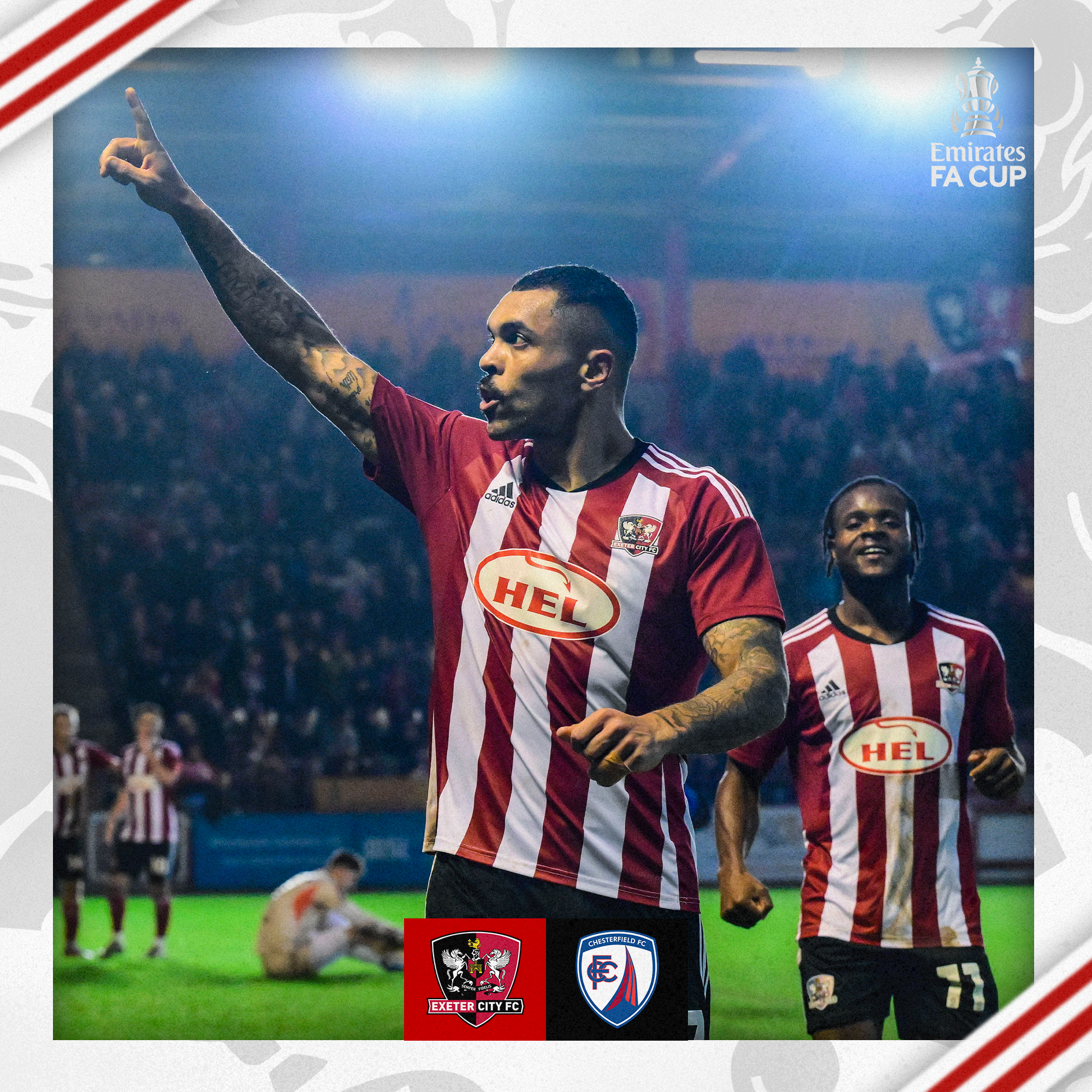 Josh Magennis celebrating scoring, by pointing into the Big Bank. He's illuminated by the floodlights behind them.