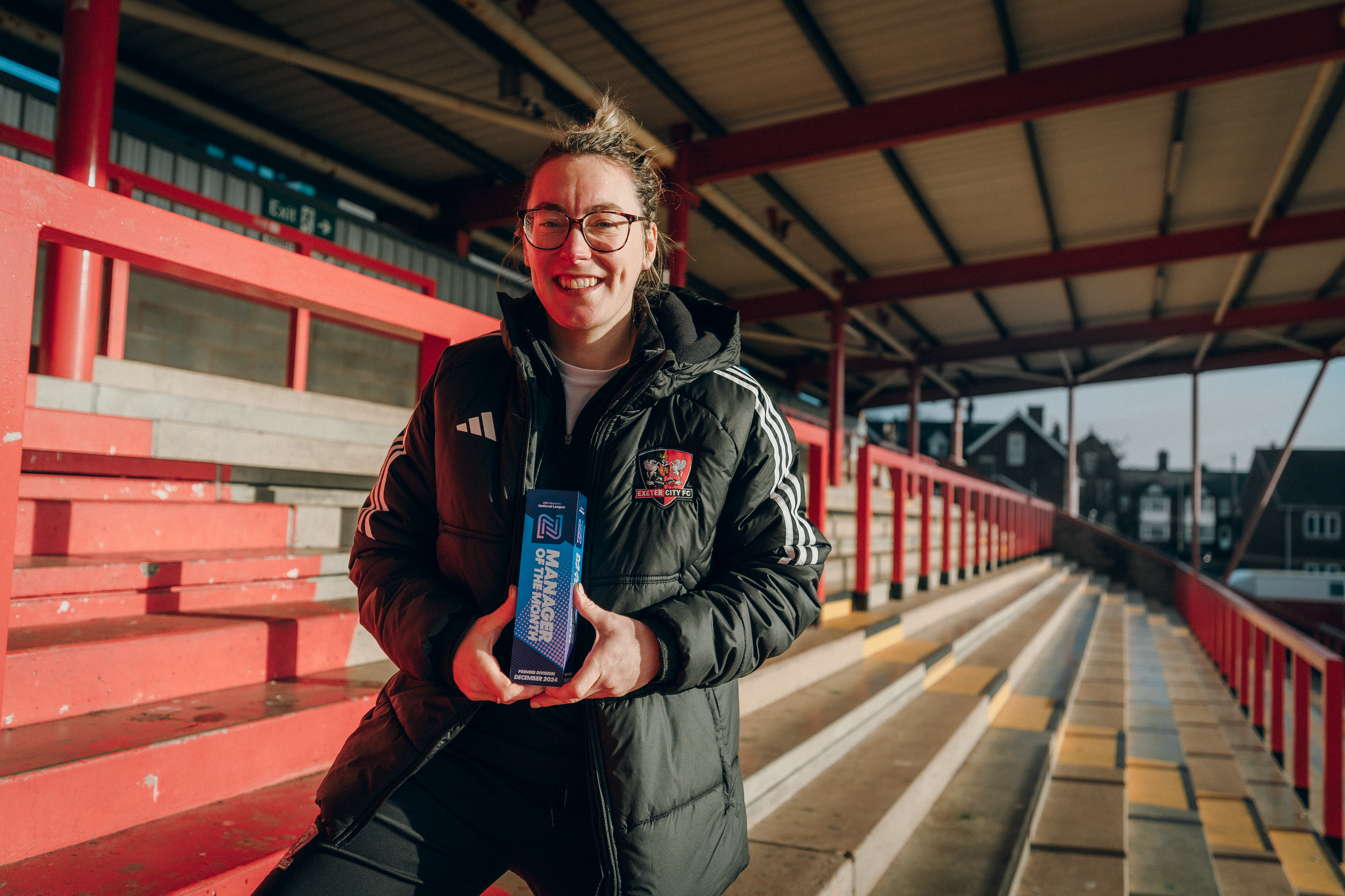 Abbie Britton holding her award in the Big Bank at Exeter City FC