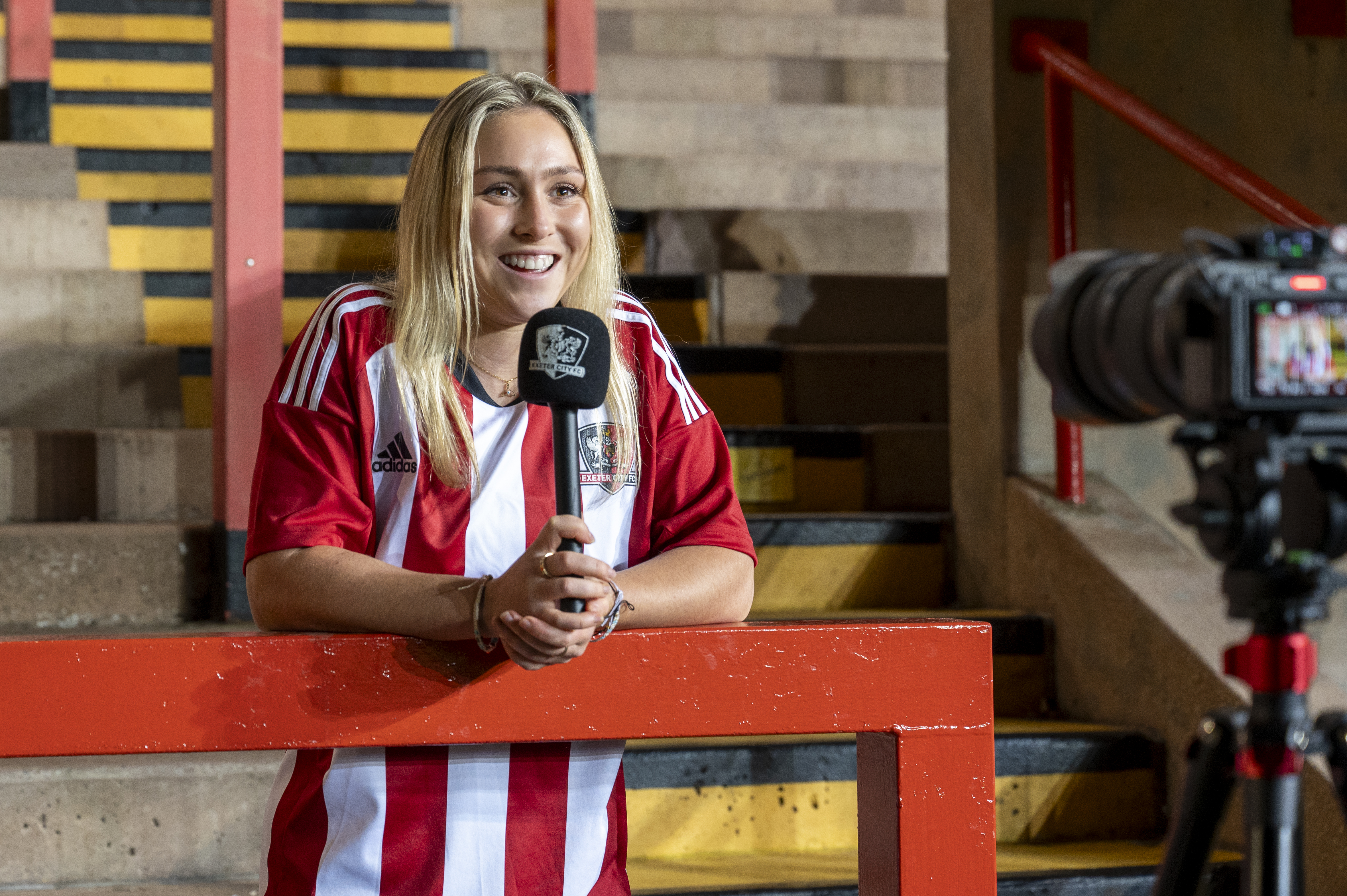 New signing, Maya Kendall, talking to the camera while holding a microphone in the Big Bank at St James Park