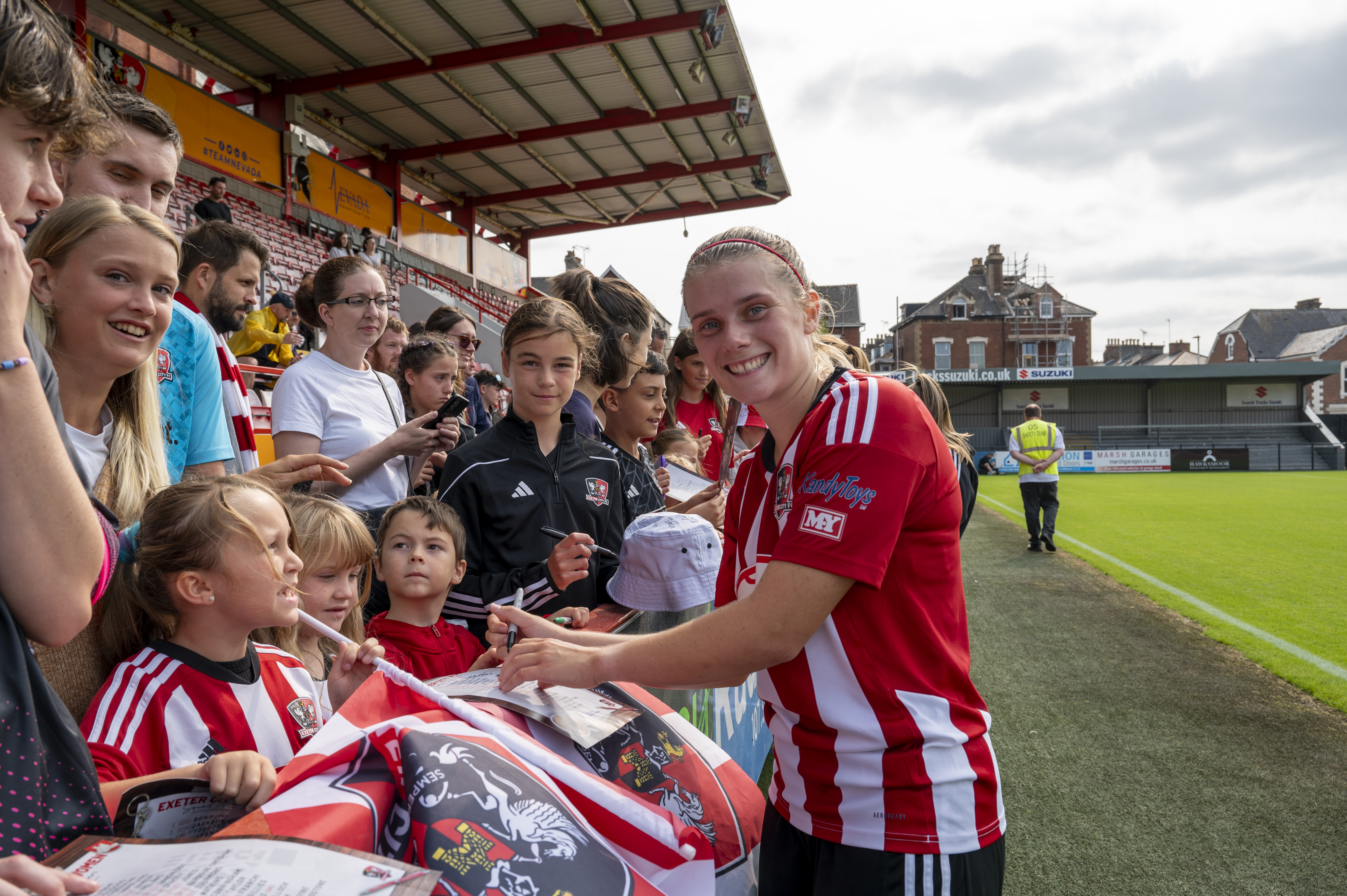 Image of Beth Ireland with young fans signing autographs