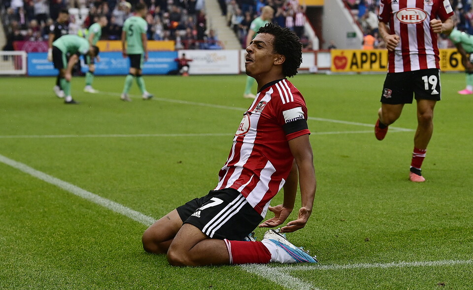 Caleb Watts knee-slides after scoring against Cheltenham Town at St James Park