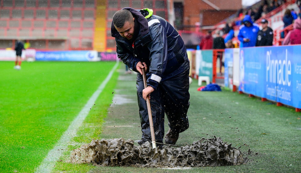 Grounds staff sweeping water off the pitch in an attempt to resume play at St James Park