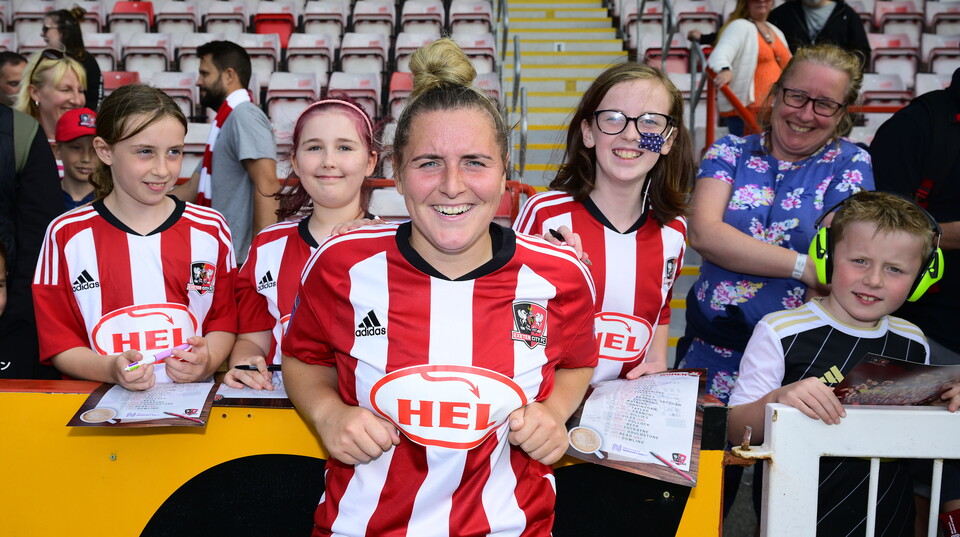 Courtney Jones resting on a barrier with several young supporters behind her.