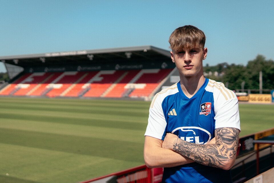 Image of Kieran Wilson crossing his arms stood with the stand behind him