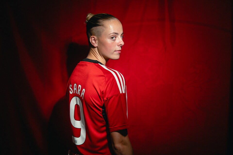 Image of Ellie Sara looking over her shoulder at the camera, with '9 Sara' clearly displayed on her back