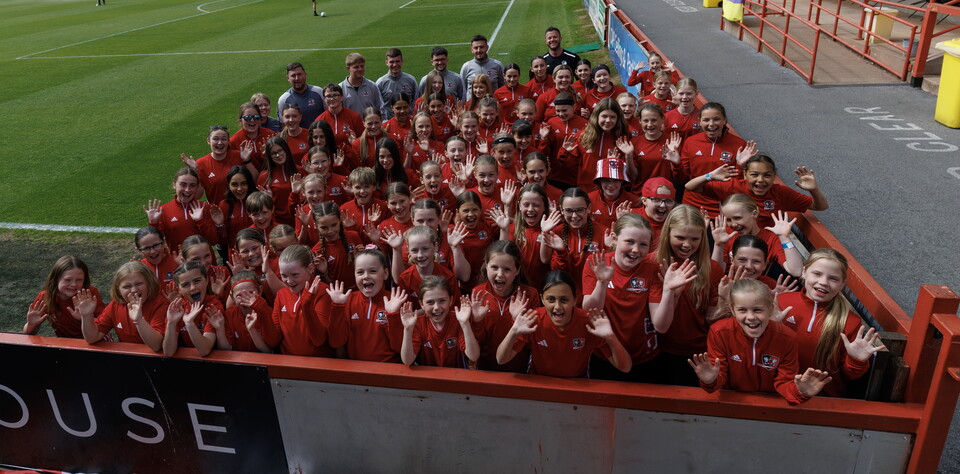 Image of the players from the girls' pathway waving at St James Park
