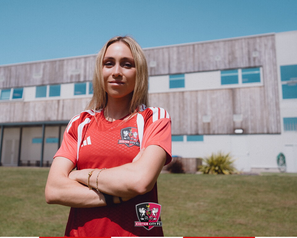 Image of Maya standing in front of the training ground building at Exeter City