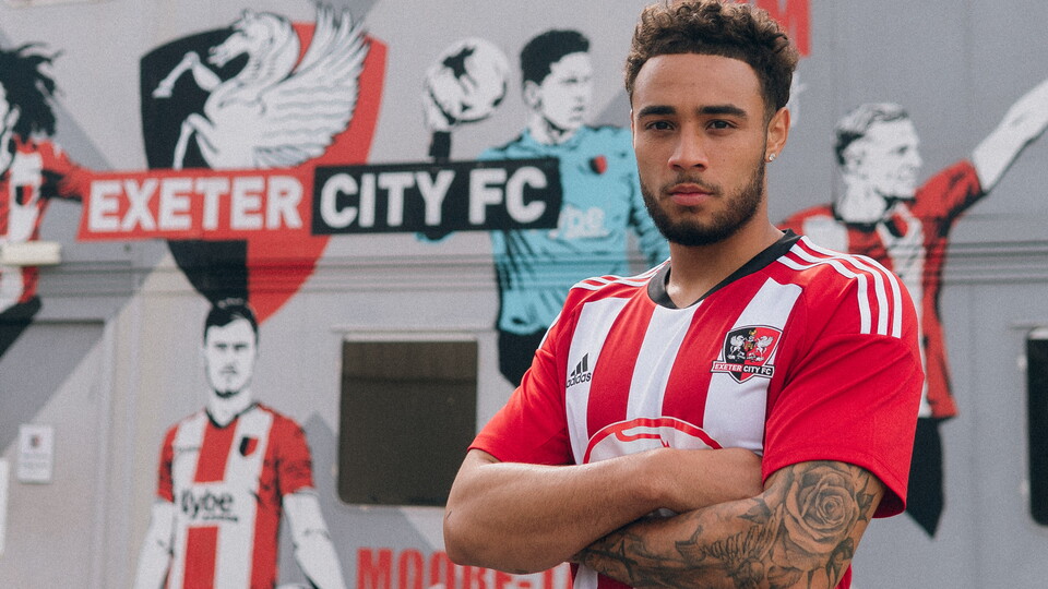 Image of Jay Bird stood in front of the ECFC academy mural